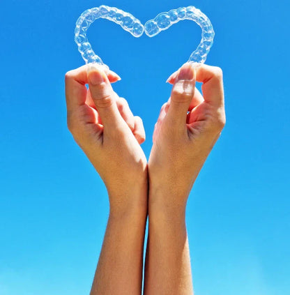 Night Shield Dental Custom Mouldable Nightguards shaped like a heart held by hands against a blue sky.