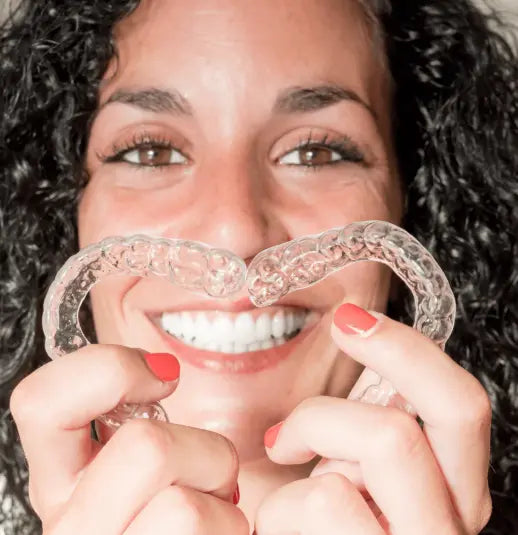 Woman holding two nightguards to face